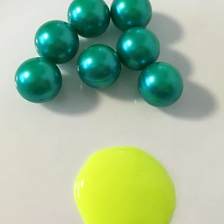 Paintballs Blast Premium de cáscara verde junto a una mancha de pintura verde neón